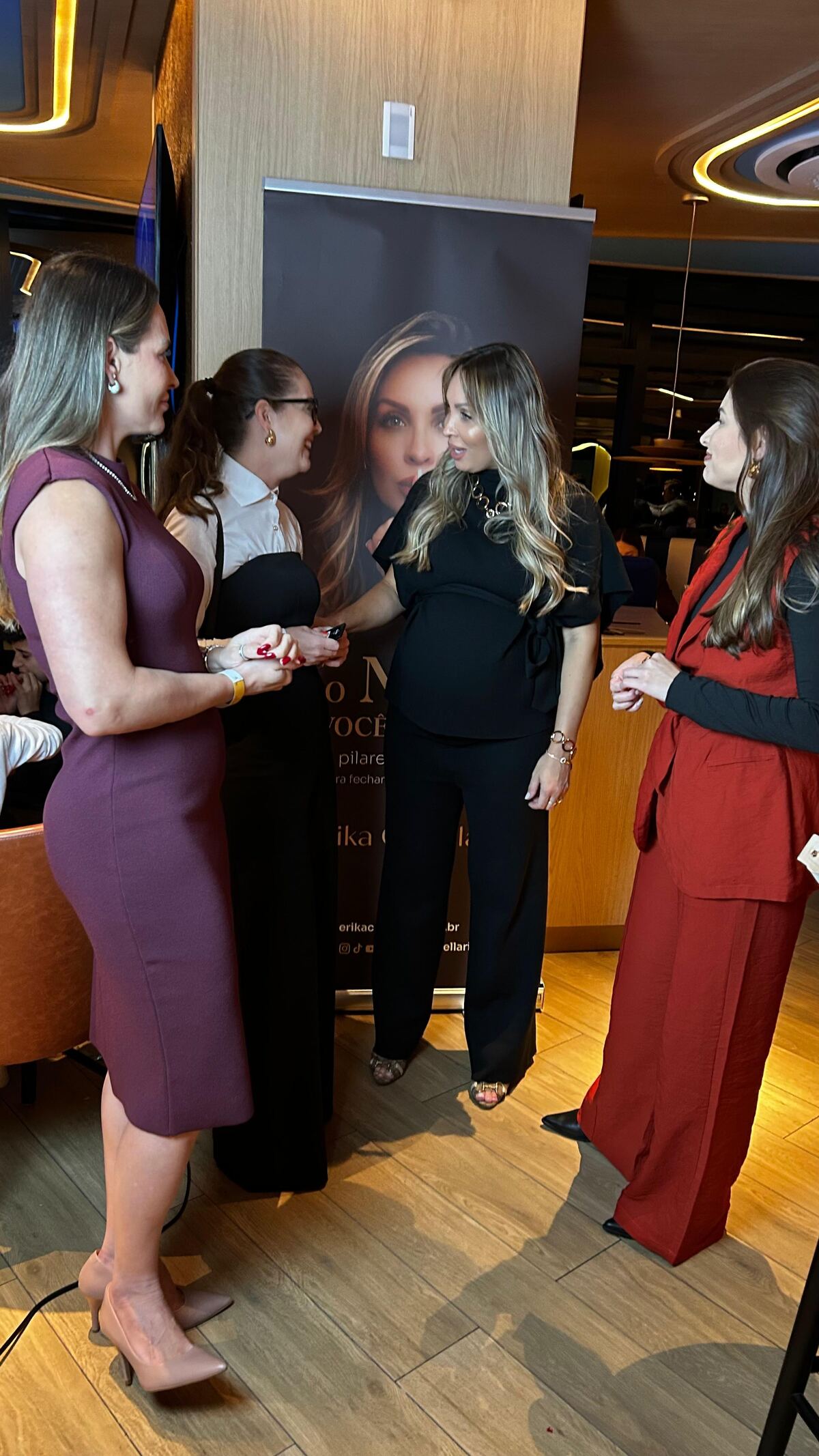 Érika conversando com convidadas ao redor do banner